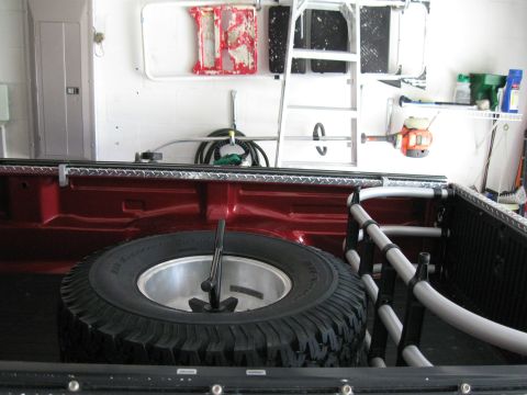 1999 Ford Ranger - The interior of a truck bed shows a spare tire and various tools and equipment stored in a garage.