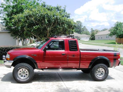 1999 Ford Ranger - A red pickup truck is parked on a paved surface in front of a residential area.