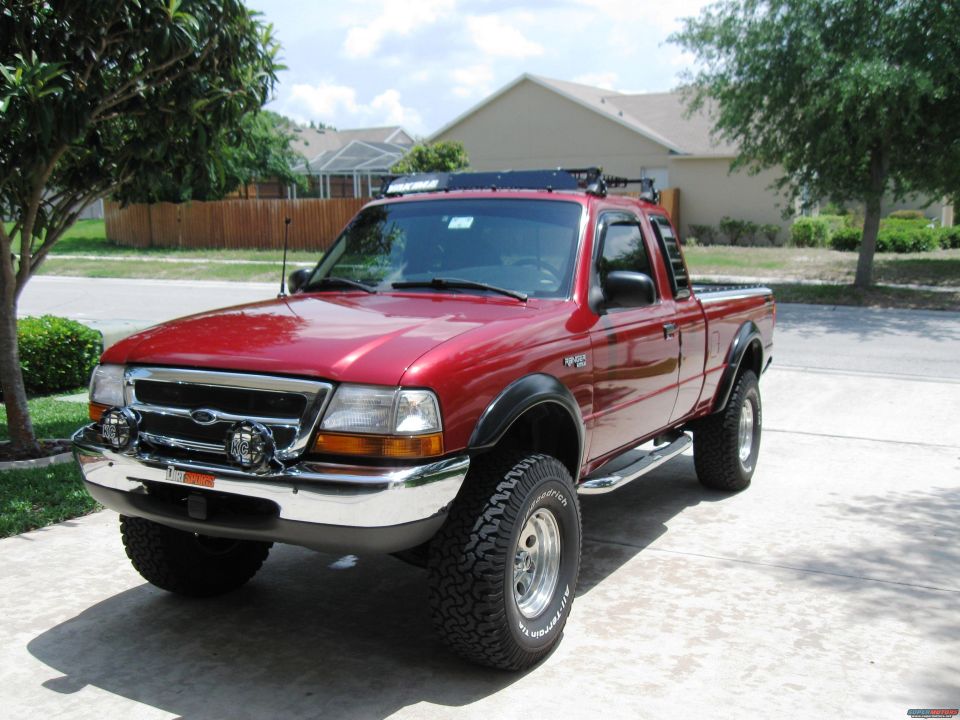 Red 1999 Ford Ranger pickup truck with roof rack and off-road tires