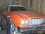 1984 Ford Mustang - Front view of an orange car with a white roof, possibly a 1979 Ford Mustang, positioned on a lift.