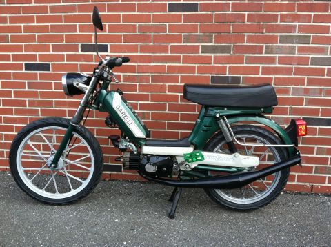 1981 Garelli Rally Sport - A green moped is parked outdoors against a brick wall, showing its side profile.