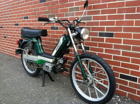 1981 Garelli Rally Sport - Green Garelli moped with white stripe on gas tank parked by a brick wall.