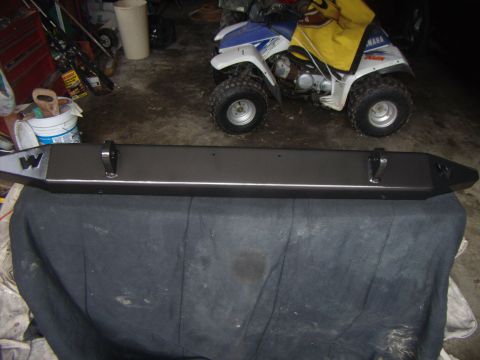 2003 Jeep Wrangler - Aftermarket bumper with tow hooks and a 'W' logo is displayed indoors.