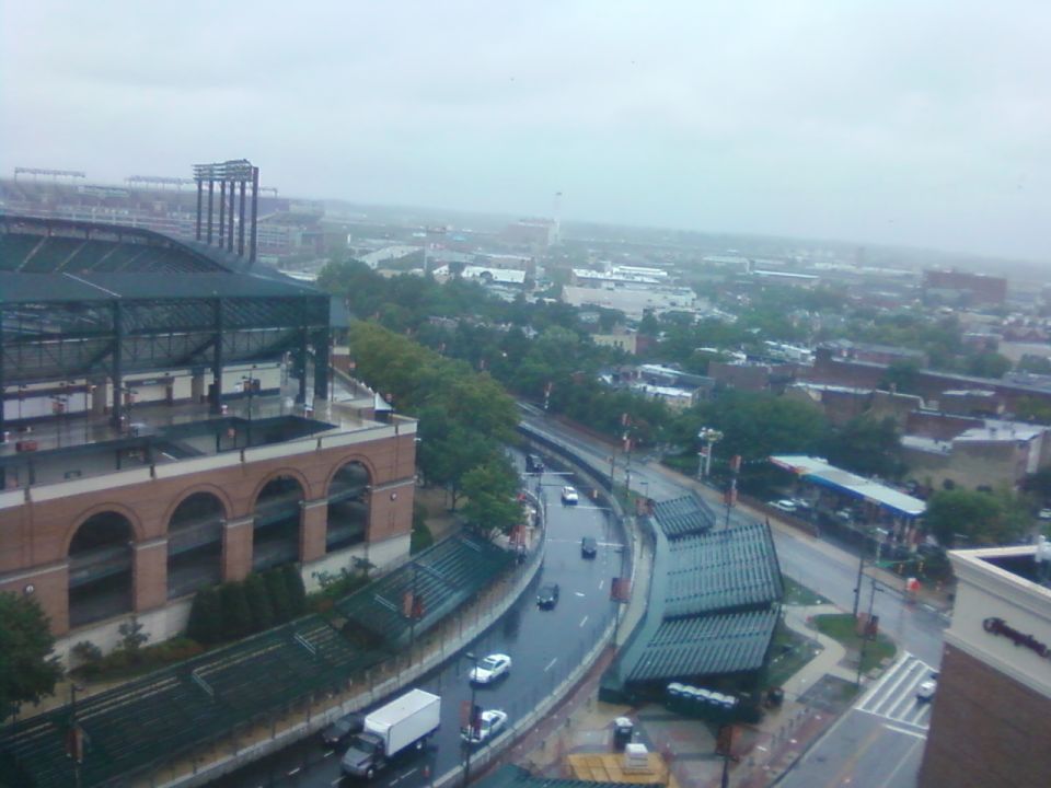 City street scene with stadium, cars, and a white truck on a rainy day
