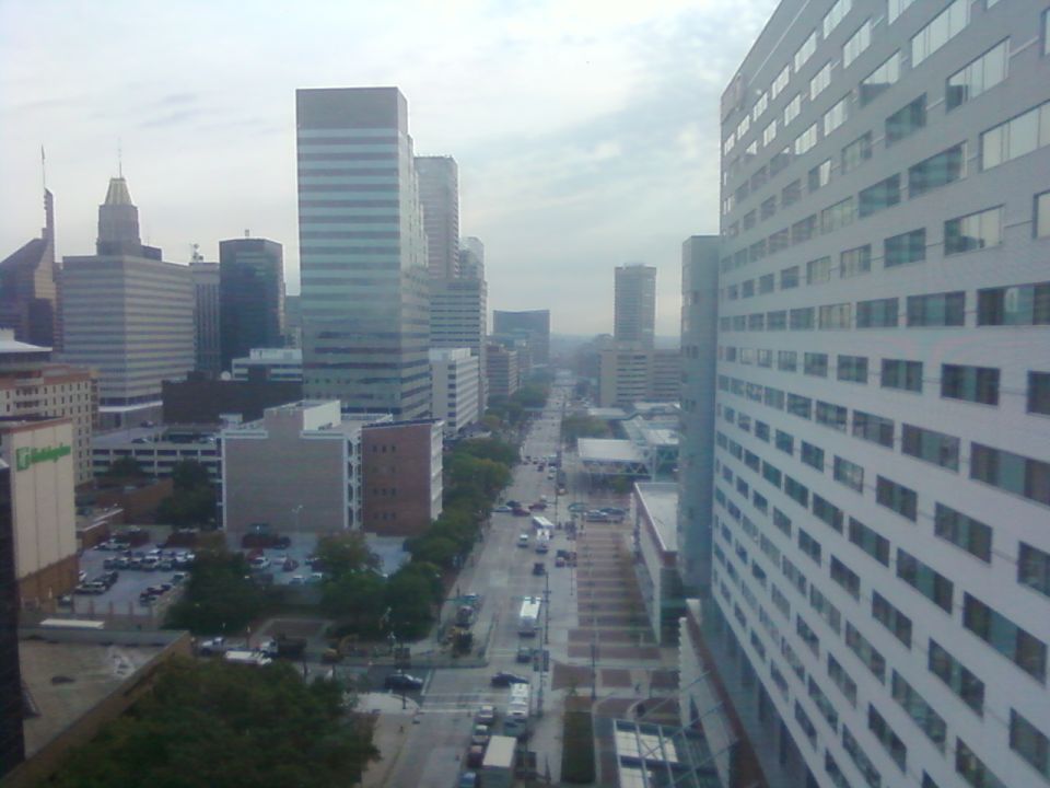 City street with tall buildings on both sides and cars driving on the road