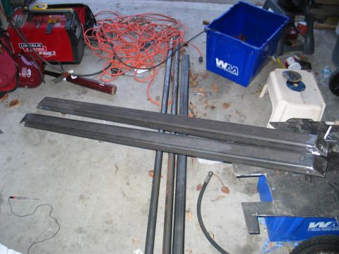 1984 Ford Bronco - Metal parts and welding equipment are laid out on a concrete floor.