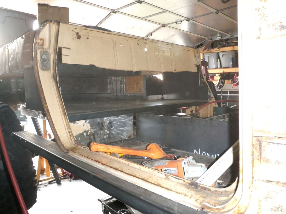 Interior of a vehicle undergoing restoration, showing bare metal, tools, and unfinished body panels