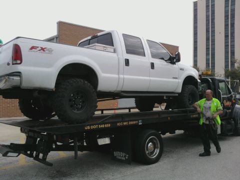 1995 Ford Bronco - A white Ford F-250 Super Duty pickup truck is loaded onto a tow truck.