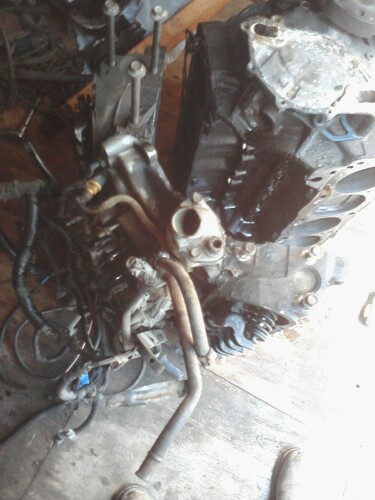 1989 Ford Bronco - A disassembled engine block with various hoses and wiring attached is shown in a workshop setting.