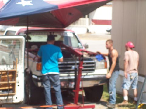 1989 Ford Bronco - Three men are gathered around a red Ford F-Series truck with its hood open, working on it outdoors.