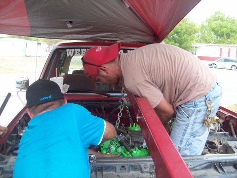1989 Ford Bronco - Two men are working on the engine of a red vehicle, with the engine painted bright green.