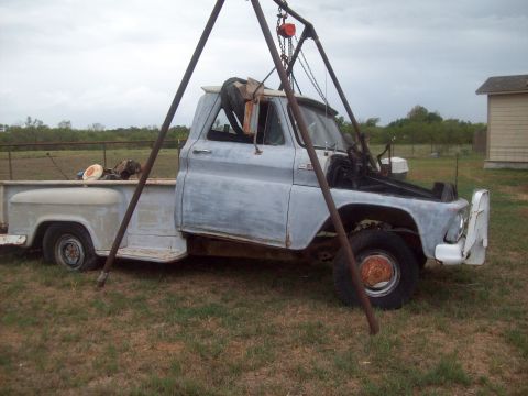 1989 Ford Bronco - Old pickup truck being worked on with an engine hoist. The truck appears to be from the 1960s.