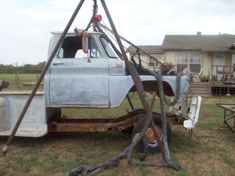 1989 Ford Bronco - This truck cab and chassis is being worked on outdoors, with a house in the background.