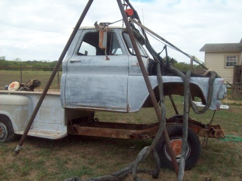 1989 Ford Bronco - This pickup truck cab is suspended by a lifting frame, revealing its bare chassis and rear wheel assembly.