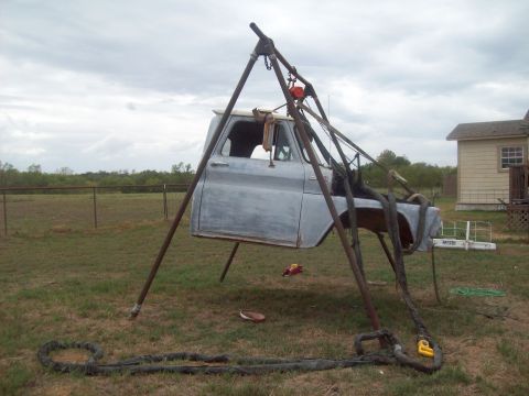 1989 Ford Bronco - A truck cab is hoisted up in a yard, awaiting restoration or repair.