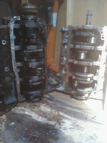 1989 Ford Bronco - Two engine blocks are shown, one a pulley system at the top, resting on a wooden surface.