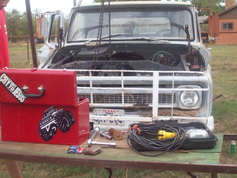 1989 Ford Bronco - A vintage truck is undergoing maintenance, with tools and a toolbox laid out on a table nearby.