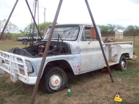 1989 Ford Bronco - A vintage pickup truck is undergoing repairs outdoors, with its engine exposed and a flat tire.