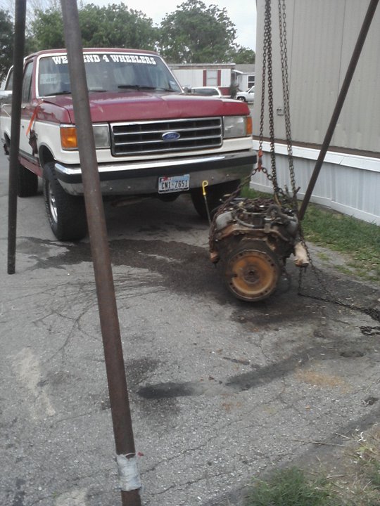 1987 Ford F-Series pickup truck with an engine being lowered next to it