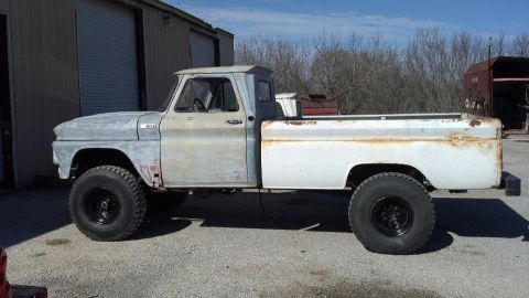 1989 Ford Bronco - This lifted pickup truck appears to be undergoing restoration, with primer on the front and a white bed.