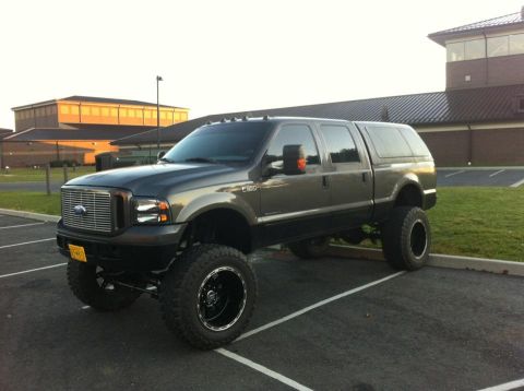 1988 Ford Bronco - This lifted Ford F-250 Super Duty pickup truck is parked in a lot, showing its front three-quarter view.