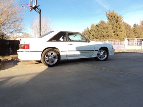 1989 Ford Mustang - A white 1989 Ford Mustang GT is parked outside on a sunny day.