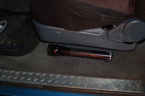 1992 Ford F-150 - A flashlight is placed on the floor mat inside a vehicle, near the seat.