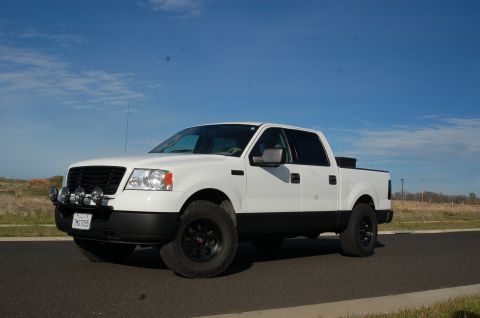 1992 Ford F-150 - This white Ford F-150 truck, likely from the mid-2000s, is parked on a paved surface under a clear blue sky.