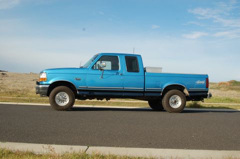1992 Ford F-150 - This blue 1992 Ford F-150 crew cab pickup truck is shown from the side under a clear blue sky.