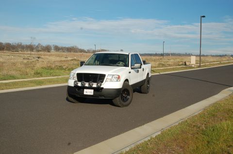 1992 Ford F-150 - White Ford F-150 pickup truck with aftermarket lights and black wheels is seen from the front.