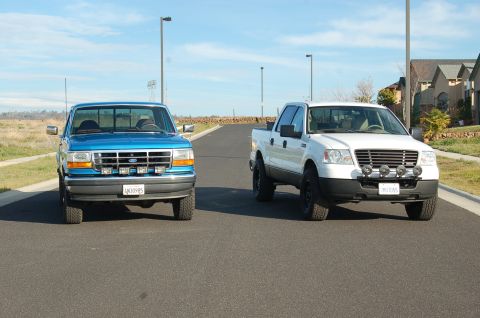 1992 Ford F-150 - Two Ford pickup trucks, a blue 1997 F-150 and a white F-150, are parked on a road with houses in the background.