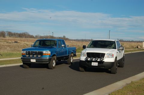 1992 Ford F-150 - Two Ford F-150 trucks, a blue 1992 model and a white later model, are parked on a suburban street under a clear blue sky.
