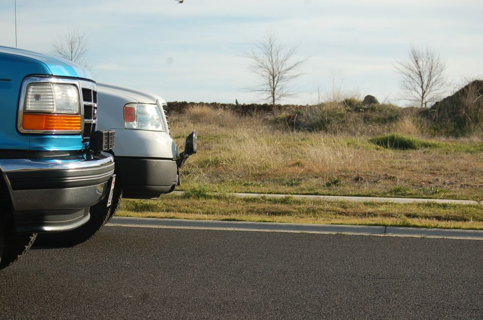 Blue 1997 Ford F-250 front corner and silver truck front corner parked on asphalt