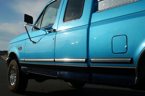 1992 Ford F-150 - The side profile of a bright blue pickup truck is shown against a clear sky.