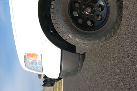 1992 Ford F-150 - Front corner of a white truck showing the fender, headlight, and a large tire with a black wheel.
