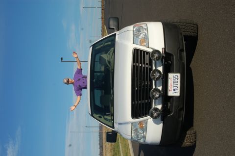 1992 Ford F-150 - A person leans out the window of a white pickup truck parked on asphalt under a clear blue sky.