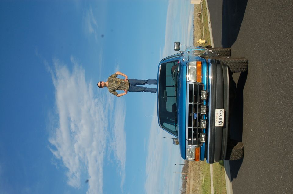 Blue 1992 Ford F-150 truck, 3q-front view, with a person standing on the roof