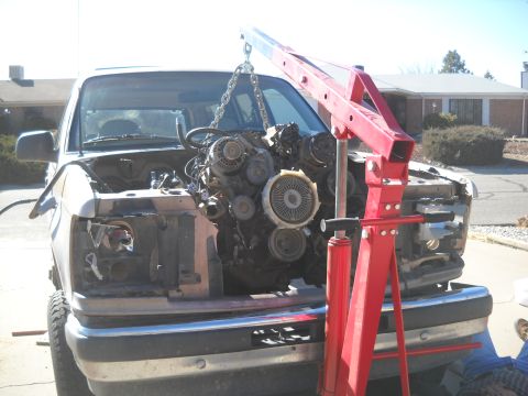 1992 Ford Explorer - Engine is being lifted out of a 1992 Ford Explorer with a red engine hoist.