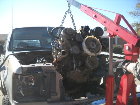 1992 Ford Explorer - An engine is hoisted out of a truck using a red engine crane, revealing the empty engine bay.