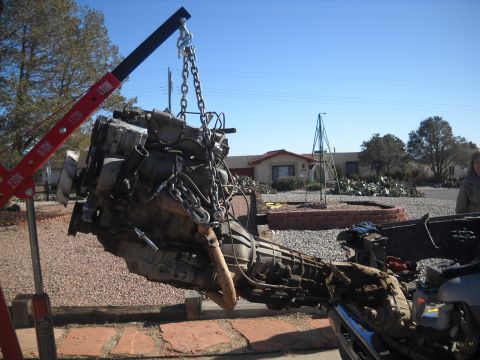 1992 Ford Explorer - An engine and transmission assembly is being lifted by a red engine hoist in an outdoor setting.