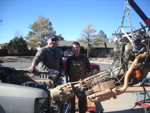 1992 Ford Explorer - Two men stand by as an engine and transmission are removed from a vehicle, likely for parts or repair.
