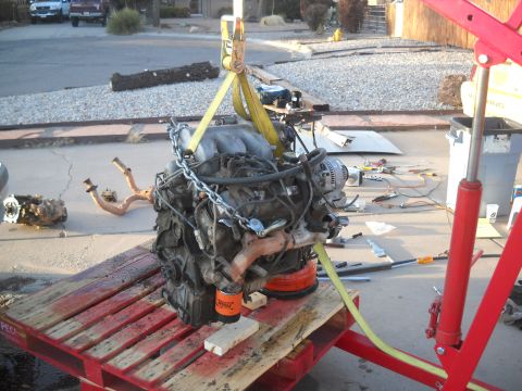 1992 Ford Explorer - An engine is suspended by chains and straps, resting on a wooden pallet, ready for removal or installation.