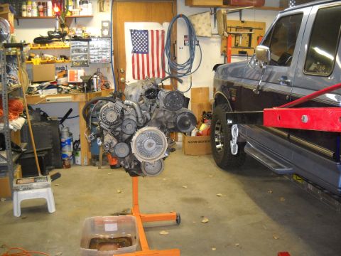 1992 Ford Explorer - An engine is displayed on an orange stand in a garage, with a Ford truck parked nearby.