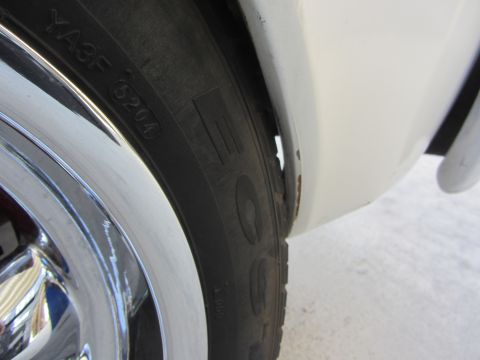 1964 Ford Ranchero - Detail shot of a tire and the rusted wheel well of a vehicle.
