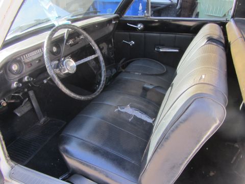 1964 Ford Ranchero - The interior of a 1964 Ford Ranchero shows its black vinyl seats, dashboard, and steering wheel.