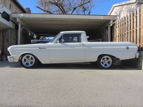 1964 Ford Ranchero - A white 1964 Ford Ranchero pickup truck is parked under a carport, with another vehicle visible in the background.