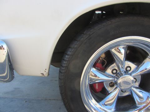1964 Ford Ranchero - White car fender and chrome wheel with red brake caliper visible.