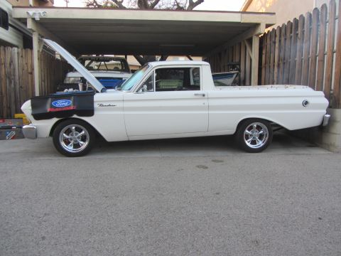 1964 Ford Ranchero - A white 1964 Ford Ranchero pickup truck is parked under a carport with its hood up, revealing another vehicle behind it.