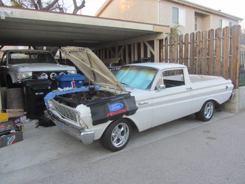 1964 Ford Ranchero - White 1964 Ford Ranchero with hood open, parked next to another vehicle under a carport.