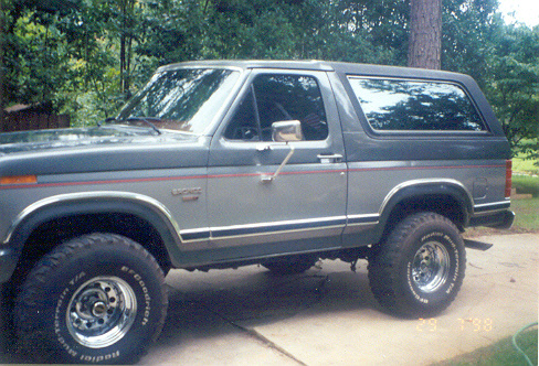 Gray two-tone full-size Bronco lifted on chrome wheels parked on a driveway